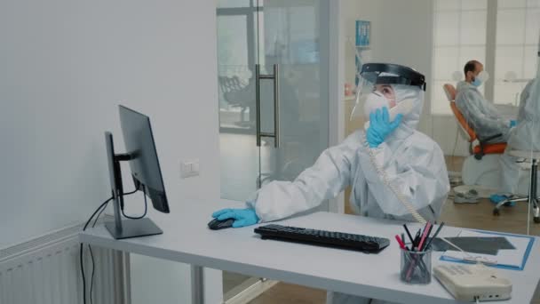 Enfermera de odontología en traje de protección sentada en el escritorio — Vídeos de Stock