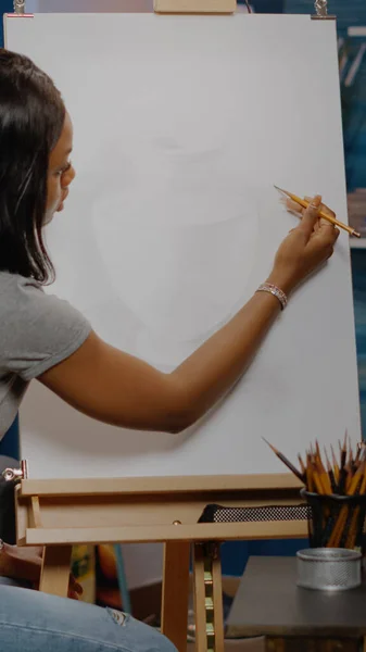 Künstler afrikanisch-amerikanischer Ethnizität zeichnet Vase auf weißer Leinwand — Stockfoto
