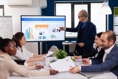 Kıdemli takım lideri konferans odasında sunum tartışmasını açıklıyor