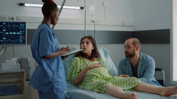 Nurse of african american ethnicity talking to pregnant patient