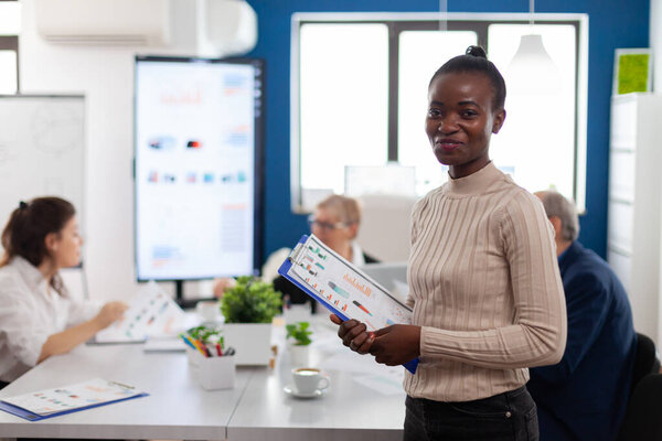 African woman manager looking at camera smiling, holding clipboard