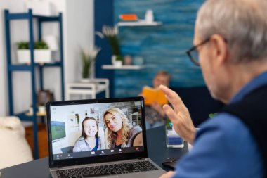 Elderly man waving at camera during online call with family
