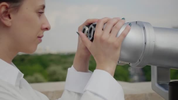 Primo piano di una giovane donna che utilizza un binocolo per visitare la città — Video Stock