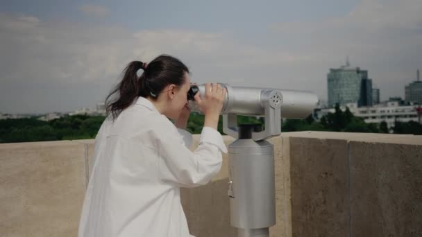 Mladý cestovatel žena pomocí dalekohledu na střeše budovy — Stock video