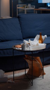 Beer bottles and pizza on table in messy living room with nobody in clipart