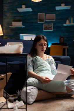 Endişeli, umutsuz, hayal kırıklığına uğramış, fatura okuyan genç bir kadın.