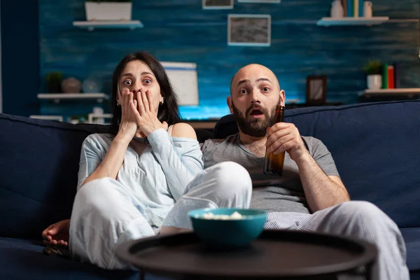 Šokovaný zmatený mladý pár sledování dokumentárního filmu v televizi — Stock fotografie