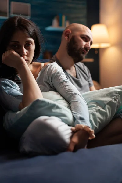 Vulnerable, scared, depressed, frustrated young couple sitting on couch