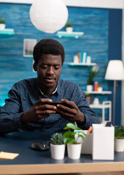 Siyah Afrikalı Amerikalı adam evde akıllı telefon kullanıyor. — Stok fotoğraf