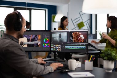 Videograf kulaklıkla müzik dinliyor, post prodüksiyon yazılımı kullanarak yaratıcılık filmi düzenliyor.