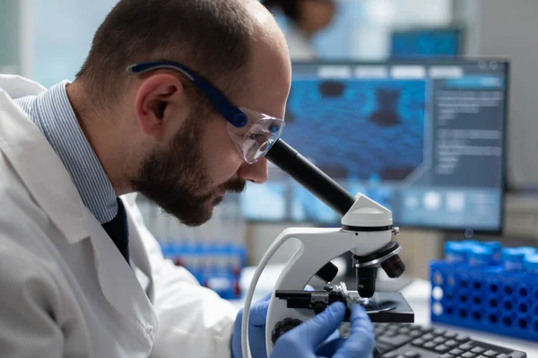 Closeup of specialist virus researcher analyzing coronavirus result using clinical microscope — Stock Photo, Image