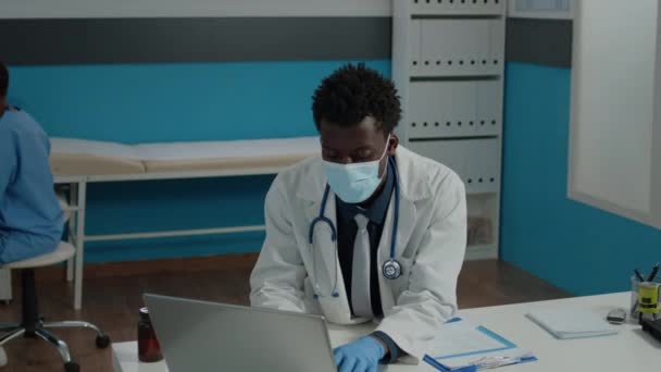 Primer plano de médico joven con mascarilla facial en gabinete médico — Vídeo de stock