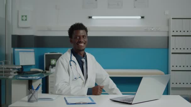 Médico varón con uniforme médico sentado en el escritorio — Vídeo de stock