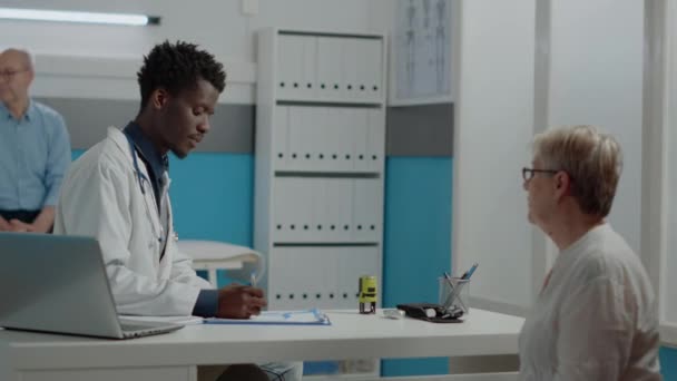 Jeune médecin utilisant timbre sur papier sur ordonnance sur le bureau — Video