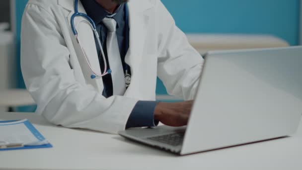 Primer plano de la escritura del médico en el teclado del ordenador portátil en el gabinete médico — Vídeos de Stock