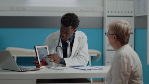 Doktor a starší pacient se dívají na obrázek srdce — Stock video