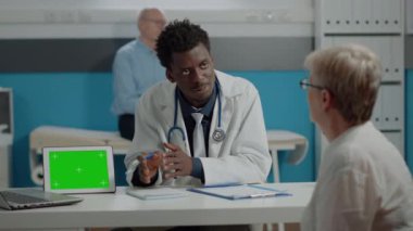 Çok ırklı doktor ve yaşlı hasta yeşil ekranlı check-up yapıyorlar.