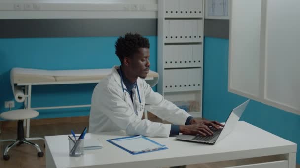 Молодой человек работает врачом в офисе врача — стоковое видео