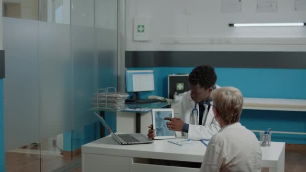 Joven fisioterapeuta mostrando tableta de lesión ósea — Vídeos de Stock