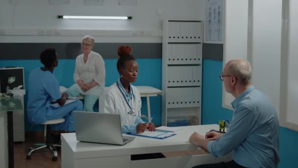 Lekarz konsultujący starszego pacjenta z chorobą w gabinecie lekarskim — Wideo stockowe