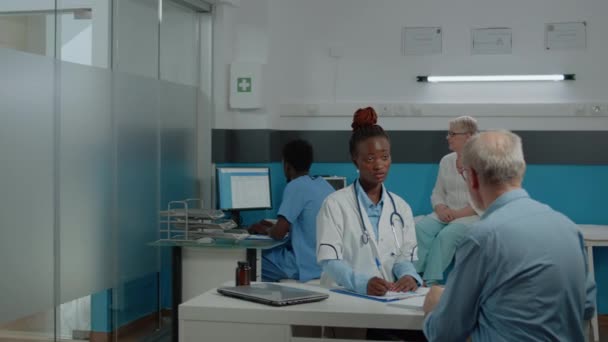 Jovem assistente médico dando raio-x ao médico sentado na mesa — Vídeo de Stock