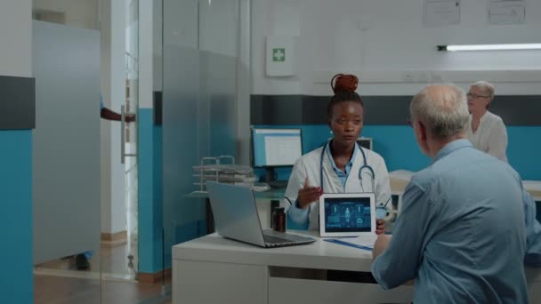Medic en senior patiënt op zoek naar tablet scherm — Stockvideo