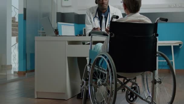 Oudere patiënt met een handicap heeft checkup afspraak — Stockvideo