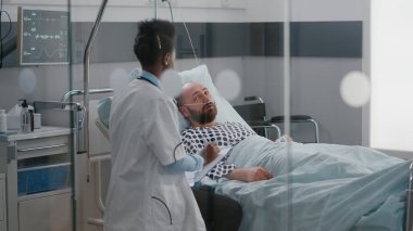 Afro-Amerikalı doktor hasta adamı kontrol ediyor. Hastalık belirtilerini izliyor.