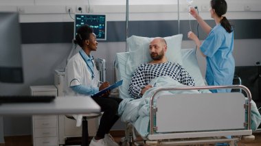 Doktor hastalık tedavisini tartışıyor. Panoya tıbbi belirtiler yazıyor.