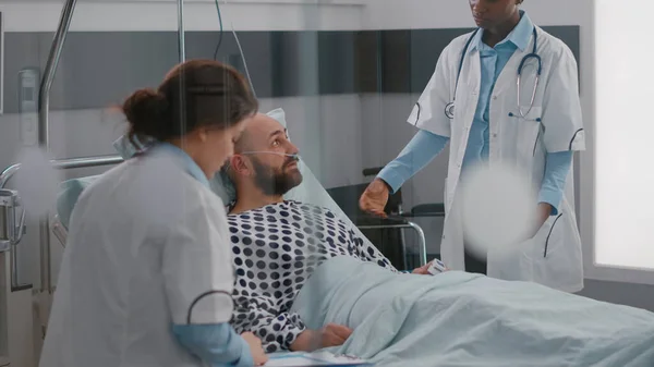 Patienten diskuterar med läkare när han ligger i sängen under sjukdomsåterställningen — Stockfoto