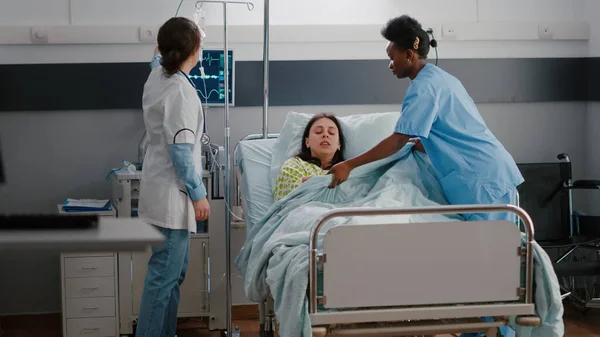 Lékařský tým pomáhá nemocné ženy ukládat do postele během nemoci stav nouze — Stock fotografie