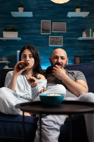 Relaxado casal animado assistindo TV no sofá relaxando tarde da noite — Fotografia de Stock