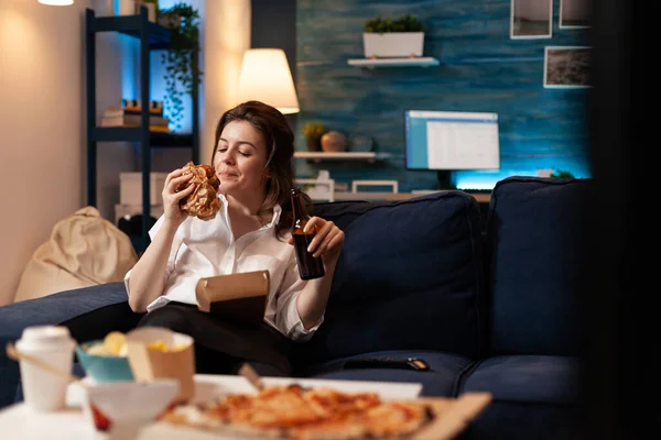 Happy vrouw eten smakelijke heerlijke levering hamburger ontspannen op bank kijken comedy film — Stockfoto