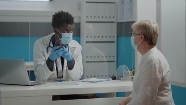 Young medic showing bottle of pills to elder patient — Stock Video