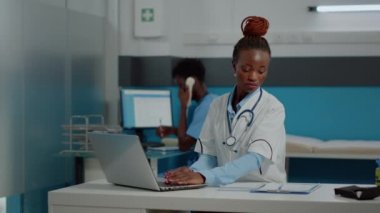 Laptop kullanan beyaz önlüklü genç doktor portresi