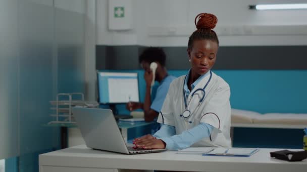 Retrato de médico joven con capa blanca usando el ordenador portátil — Vídeo de stock