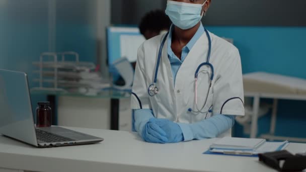 Doctor de etnia afroamericana sentado en el escritorio con el ordenador portátil — Vídeo de stock