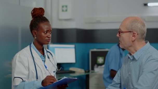 Κοντινό πλάνο του Αφροαμερικανού γιατρού που μιλάει με τον ανώτερο ασθενή. — Αρχείο Βίντεο