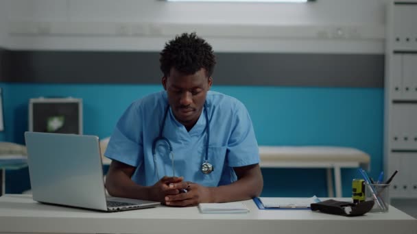 Közelkép fekete orvosi asszisztens mosolyog ül az asztalnál — Stock videók