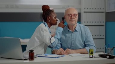 Genç uzman otoskopla kulak muayenesi yapıyor.