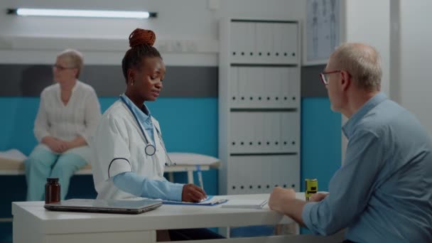 Mladý medik vysvětluje rentgen starému muži za stolem — Stock video