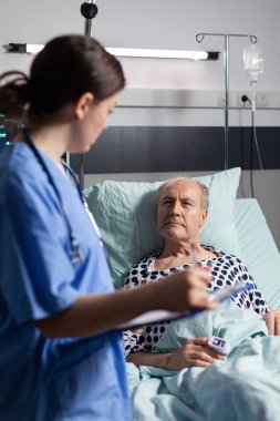 Tıbbi asistan yaşlı adamın tedavisini kontrol ediyor.