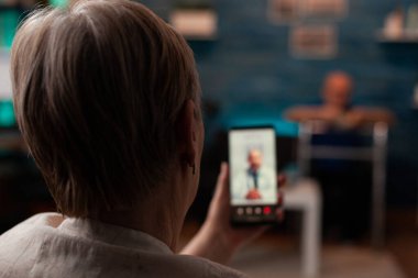 Video ile akıllı telefon tutan emekli kadın.