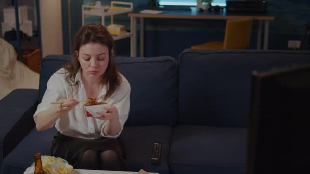 Persona comiendo fideos asiáticos con palillos en el sofá — Vídeo de stock