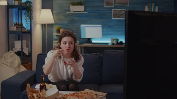 Woman eating chinese food from takeaway place sitting on sofa — Stock Video