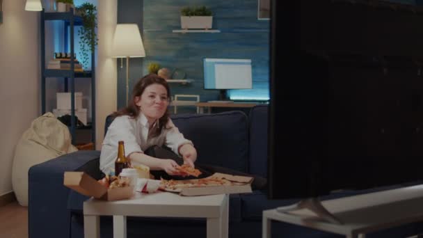 Pessoa comendo fatia de pizza enquanto assiste comédia na TV — Vídeo de Stock