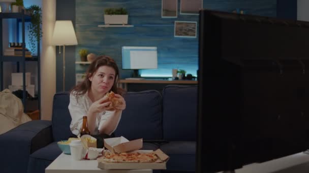 Person eating delicious hamburger and fries in living room — Stock Video