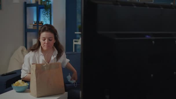 Woman with face mask sitting on couch with food delivery — Stock Video