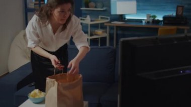 Paketinden yemek çıkaran beyaz bir yetişkin.