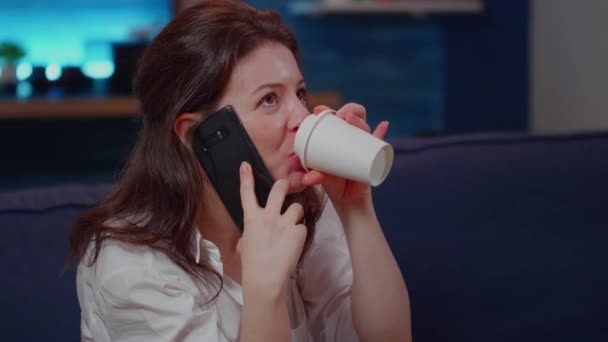 Νεαρή γυναίκα πίνει ποτό ενώ μιλάει στο smartphone — Αρχείο Βίντεο
